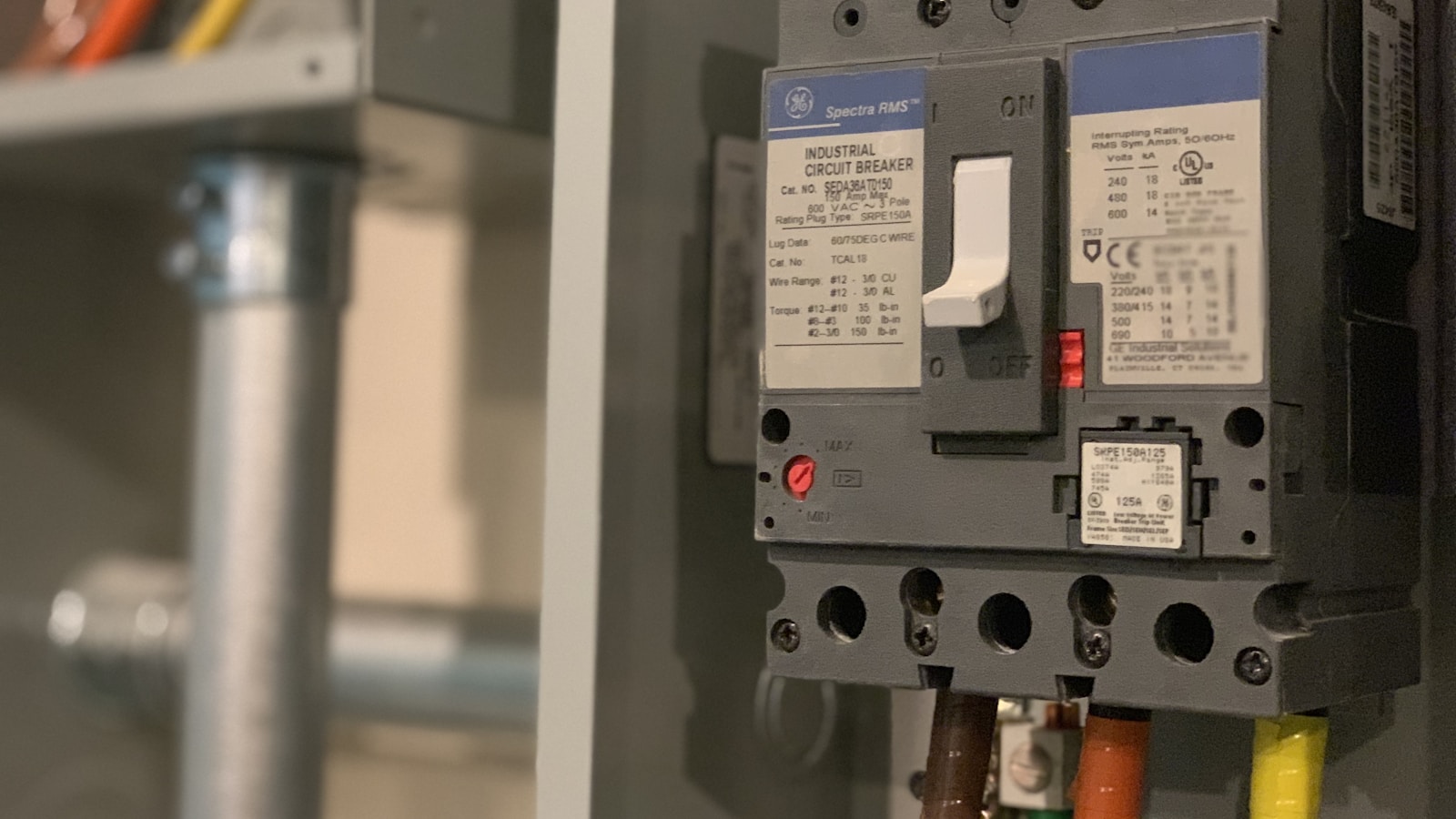 Armoire électrique industrielle ouverte avec disjoncteurs et étiquettes de repérage