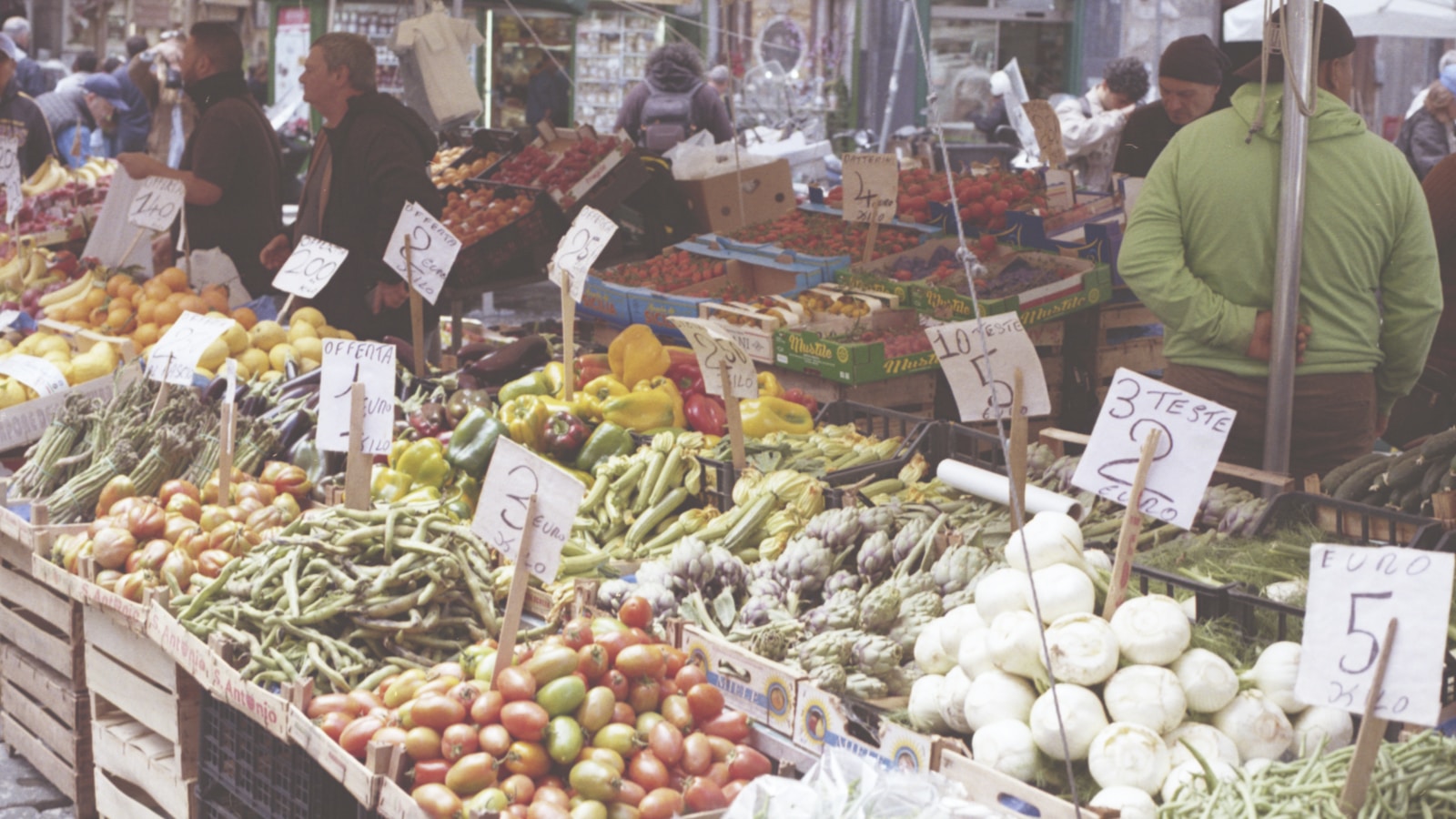 Étal de primeur sur un marché de plein air avec écriteaux de prix et mention d'origine